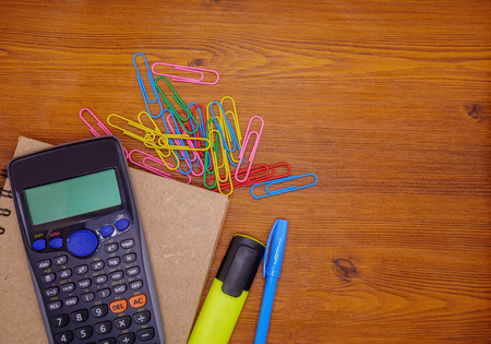 Top view notebook,calculator and stationery on brown wooden table