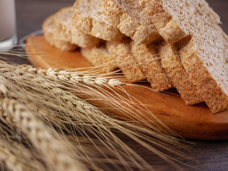 Sliced breads in wooden plate with rive plants and milk on wooden table Food,bakery,still life conceptの写真素材