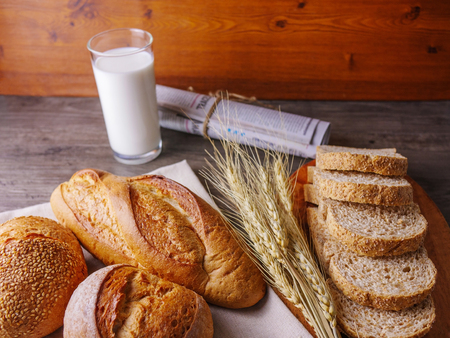 Various of breads on wooden table with milk and newspaper breakfast table with copy space  Food,bakery,nature conceptの写真素材