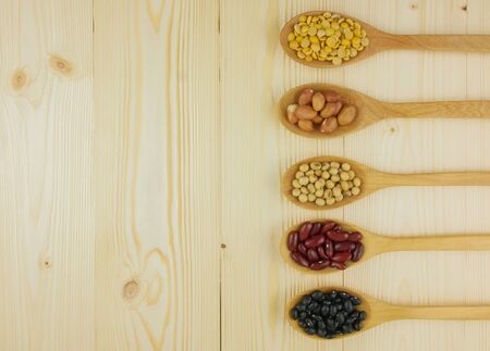 Flat lay,top view assorted beans including red bean,soybeans,black beans,mung beans on brown,beige wooden background with copy spaceの写真素材