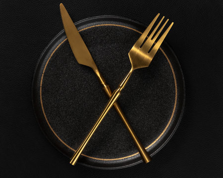 The golden tableware is placed on a ceramic dinner plate. The background is black leather....