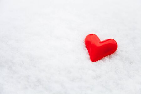 Ceramic red heart on the fresh snow backgroundの写真素材