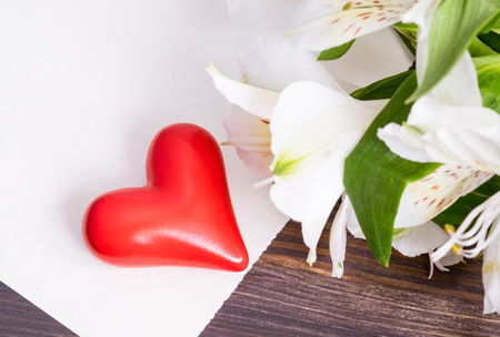 Ceramic red heart and an empty sheet of paper on wooden backgroundの写真素材