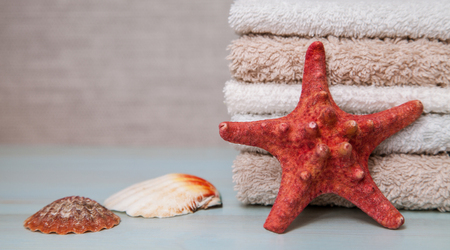 Neatly folded towels and a red starfish and shells - closeup shot- closeup shotの写真素材