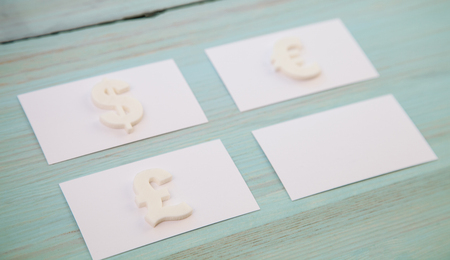 Empty business cards and symbols of different currencies on wooden background