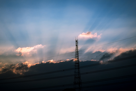 Sihouette high voltage pole The sunset Light through the clouds on the sky.の写真素材