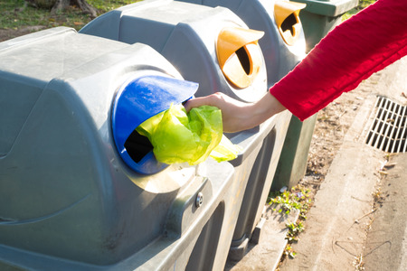 Women hand throwing plastic bag in recycling bin to help environmental protection and Waste separation reduce global warmingの写真素材