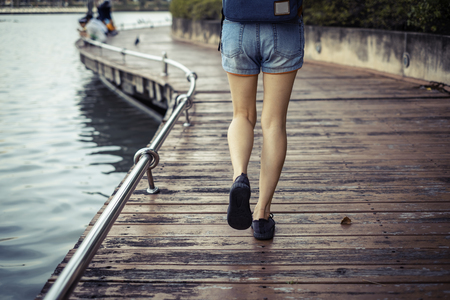 Close up foot. Girl is walking on the street Wood bridge riverside in the public park.の写真素材