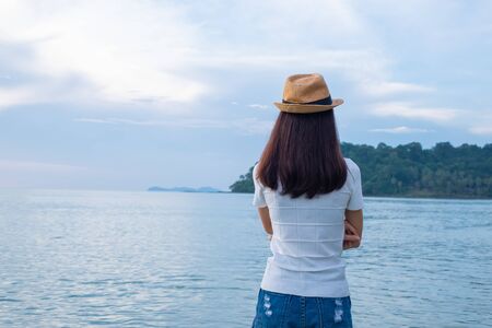Asian woman tourists on the beach watching the beautiful sea view. the clear skies with clouds. Is a tourist destination that is perfect for relaxing on holidays. At Ko Kood, Trat province, Thailand.の写真素材