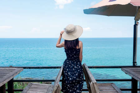 Asian women tourists go to the sea, sit by the sand, beach With beautiful blue sea views Suitable...