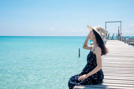 Asian woman tourists Sitting on a wooden bridge at the beautiful sea view. the clear skies with clouds. Is a tourist destination that is perfect for relaxing on holidays.の写真素材