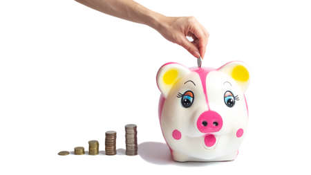 The hand is holding the coin into the piggy bank. on a white background. This coin is denominated in Thai baht. Arrange the coins into a bar chart showing business and financial growth.の写真素材