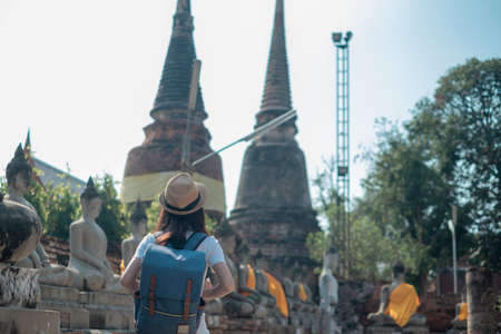 Asian woman tourists carrying a backpack and wearing a hat Visit Wat Yai Chaimongkol, the historical archaeological site of Phra Nakhon, Ayutthaya.の写真素材