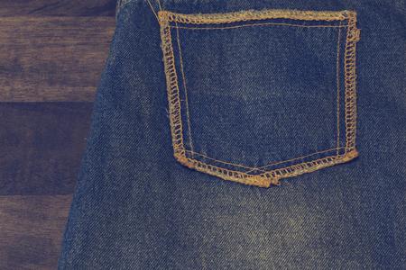 Close up up of fancy washed blue jeans pocket. On oak wood texture background, Ripped jeans of a stack Hipster fashion copy space for textの写真素材