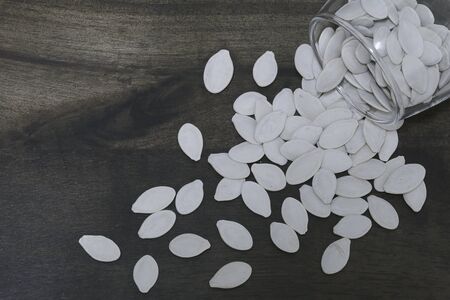 Roasted Salty Pumpkin Seeds in the glass bowl over wooden background close upの写真素材