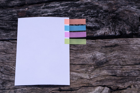 Abstract white paper with colors note tab. Notebook with colors note tab on wooden table background,...
