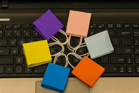 Small colorful paper shopping bags flat lay of circle around on computer notebook keyboard.Concept about online shopping or E-commerce that everything can be bought easily by using an internet.の写真素材