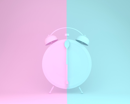 Creative layout made of spoon and fork on round plate in a form of alarm clock on pink and blue pastel background. minimal idea business concept.の写真素材