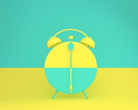 Creative layout made of spoon and fork on round plate in a form of alarm clock on yellow and green pastel background. minimal idea business concept.の写真素材