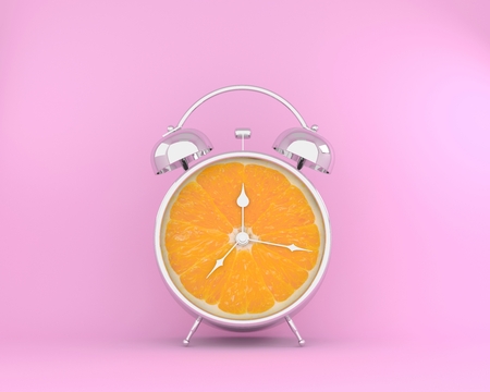 Tropical fruit concept made of orange slice alarm clock on pink pastel background. minimal idea business concept.の写真素材