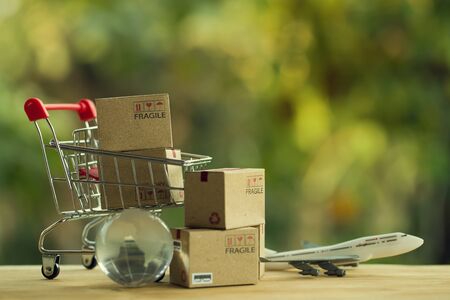 Shopping Online and e-commerce concept: Paper boxes in a shopping cart and crystal globe, plane....