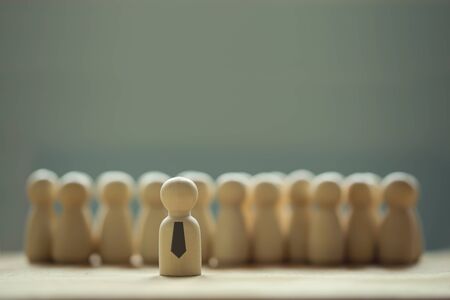 Successful business team leader concept: Wooden figures of man and people standing out from the crowd. depicts ability of individual to influence and lead followers or other members of organization.の写真素材