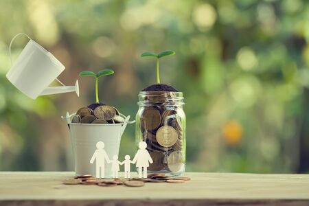 Banking and finance, Saving money concept: Water being poured on green sprout with glass bottle and bucket full of coins with family members. depicts investing money for earning growth.の写真素材