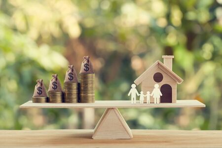 Property investment and house mortgage concept: Wooden home, Family member and US money bags on rows of rising coins on wood balance scale. depicts family financial management for a residence.の写真素材