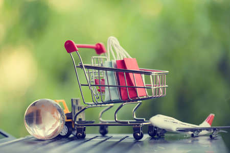 Online shopping, e-commerce concept: Paper shopping bags in a trolley or shopping cart in the natural green background. purchase of products on internet can purchase goods from foreign countries