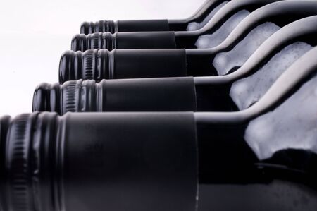 Dark wine bottles in a row against a white background.の写真素材