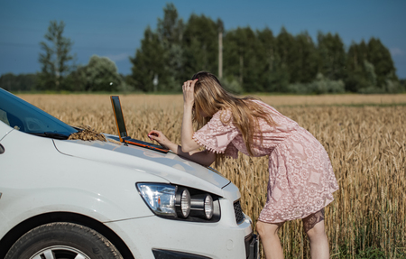 Girl working on a laptop near the field with wheatの写真素材