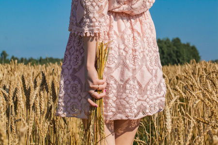 Girl walking on the field with wheatの写真素材