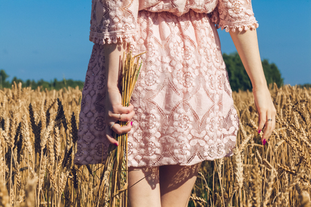 Girl walking on the field with wheatの写真素材