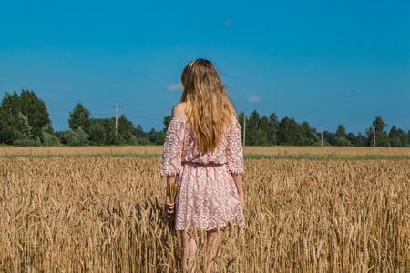 Girl walking on the field with wheatの写真素材