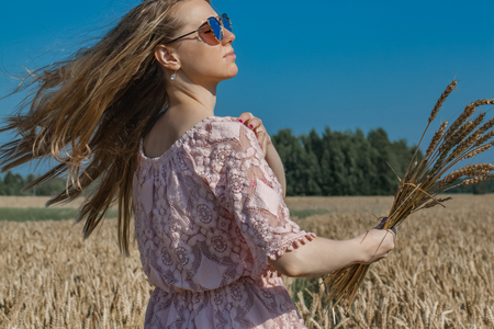 Girl walking on the field with wheatの写真素材