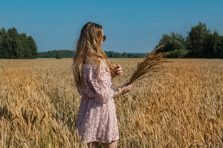 Girl walking on the field with wheatの写真素材