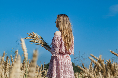 Girl walking on the field with wheatの写真素材