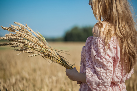 Girl walking on the field with wheatの写真素材
