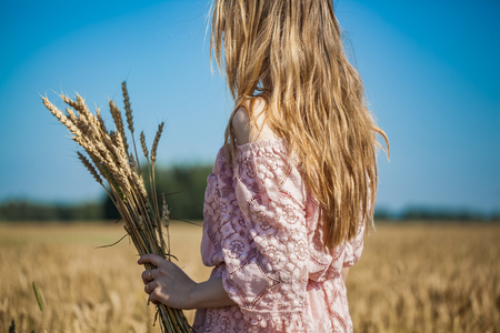 Girl walking on the field with wheatの写真素材