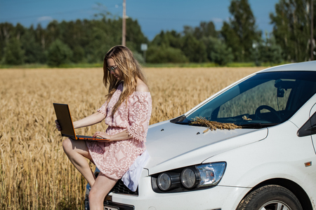 Girl working on a laptop near the field with wheatの写真素材