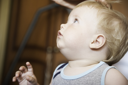 A cute little baby is looking up. The baby could be a boy or girl and has blue eyes. use it for a parenting or love concept.の写真素材