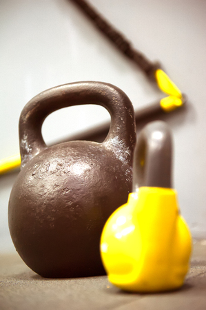Colorful kettlebells weights on gym floor - focus on the dark kettle bellの写真素材