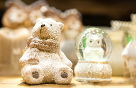 Cute white Christmas teddy bear made of porcelain is on the shelf in the background of other toysの写真素材