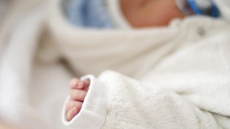 Dolly shot of the hand on a newborn baby face shallow depth of field