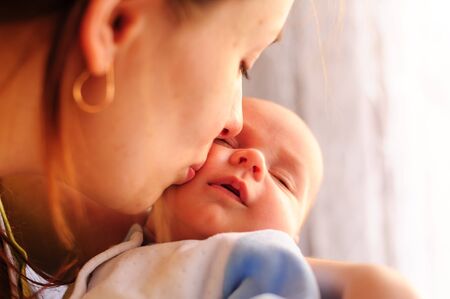 Young mother kissing her little newborn baby