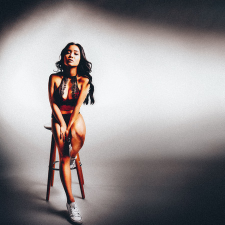 full body shot of Fashion vogue style portrait of young sexy beautiful asian woman in red overalls sitting on chairの写真素材