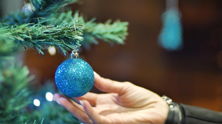 Female hands hanging balls on the Christmas tree. Winter holidays Christmas and New Year Decoration. Blinking Garland. Christmas Tree Lights Twinkling.の写真素材