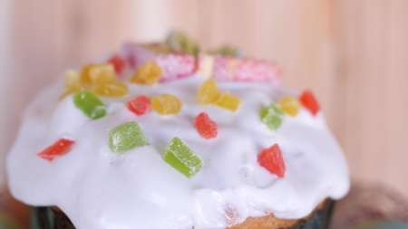 a traditional Easter cake glazed and decorated with marmalade and candied fruits is rotating with...