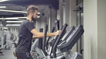 Young Muscular Man Exercising on Trainer Ellipsoid Machine. in the background with a gym facilityの写真素材