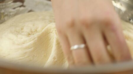 Man or woman knead the yeast dough in a bowl with his hands. Home bakery. Private business. Slow...